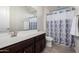 This bathroom has a grey patterned shower curtain, dark vanity and wood-look tile floors at 5539 S Verde --, Mesa, AZ 85212