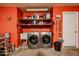 A utility room with red walls, washer, dryer, shelving, and storage space at 592 Leisure World --, Mesa, AZ 85206