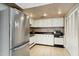 This kitchen has white cabinets, black countertops, a stainless steel refrigerator, and tile flooring at 6009 N 79Th St, Scottsdale, AZ 85250