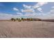 Expansive gravel front yard leading to a charming single-story home under a blue sky with puffy white clouds at 6786 W Appaloosa Trl, Coolidge, AZ 85128