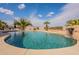 Sparkling pool with rock waterfall feature and palm trees creating a serene backyard oasis at 6786 W Appaloosa Trl, Coolidge, AZ 85128