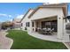 A relaxing backyard with artificial grass, a covered patio seating area, and a well-maintained stucco home at 6890 W Remuda Dr, Peoria, AZ 85383