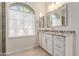 Bright bathroom featuring a granite-topped vanity, ample counter space, and a large window at 7130 W Linda Ln, Chandler, AZ 85226