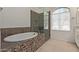 Elegant bathroom featuring a soaking tub and glass-enclosed shower, complemented by tile flooring at 7130 W Linda Ln, Chandler, AZ 85226