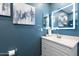 Bathroom featuring a white vanity with lighted mirror and blue accent wall with artwork at 790 N Meadows Dr, Chandler, AZ 85224