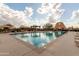 Community pool featuring lounge chairs, pergolas and desert landscaping under a sunny, partly cloudy sky at 8142 S Open Trail Ln, Gold Canyon, AZ 85118