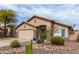 This desert home features a two-car garage and xeriscaping with mature trees, cacti and shrubbery at 8204 W Tonto Ln, Peoria, AZ 85382