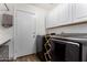 Well-lit laundry room with white cabinets, modern appliances and convenient folding rack at 8204 W Tonto Ln, Peoria, AZ 85382