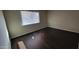 This bedroom has dark brown vinyl floors, a bright window, and neutral-colored walls at 8815 W Columbus Ave, Phoenix, AZ 85037