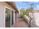 Outdoor red brick patio and sidewalk extends from a sliding glass door, surrounded by mature trees and a stucco wall at 934 E Cochise Dr, Phoenix, AZ 85020