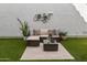 Outdoor patio area with a wicker seating set, decorative wall art, travertine tile and artificial turf at 964 S Henry Ln, Gilbert, AZ 85296