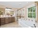 Bright bathroom with a tub, glass-enclosed shower, and a window overlooking the backyard at 964 S Henry Ln, Gilbert, AZ 85296