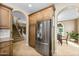 Kitchen area with stainless steel refrigerator, wood cabinets, and arched doorway leading to a dining area at 964 S Henry Ln, Gilbert, AZ 85296