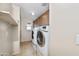 This practical laundry room features a washer and dryer, cabinets, and neutral tile at 964 S Henry Ln, Gilbert, AZ 85296