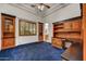Home office with custom built-in wood cabinets, blue carpet, and a ceiling fan at 10396 N 133Rd St, Scottsdale, AZ 85259
