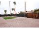 Landscaped backyard with gravel, palm trees, string lights, black wall, and a patch of grass at 1058 W Emelita Ave, Mesa, AZ 85210