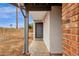 Covered entryway features a gray painted front door, leading into the home with desert landscaping, and red brick accents at 1210 E Harmony Cir, Mesa, AZ 85204