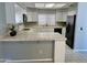 Traditional-style kitchen with white cabinetry, tile countertops and a black refrigerator at 13517 N 102Nd Pl, Scottsdale, AZ 85260