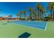 Well-maintained tennis court surrounded by lush palm trees on a sunny day at 15022 W Cooperstown Way, Surprise, AZ 85374