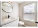 Modern bathroom vanity with round mirror, sink, toilet, and natural light from the window at 15039 S 28Th St, Phoenix, AZ 85048
