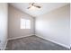 This bedroom features a ceiling fan, large window, carpeting, and neutral paint, creating a serene atmosphere at 15039 S 28Th St, Phoenix, AZ 85048
