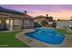 Backyard featuring a sparkling blue swimming pool, lush green lawn, and stylish tiled roofing at 1635 E Silverwood Dr, Phoenix, AZ 85048