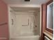 Close up of a white bathtub and shower combination with safety bars and handheld shower head, emphasizing accessibility at 18034 N 129Th Ave, Sun City West, AZ 85375