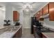 A long, galley style kitchen with dark wood cabinets and black appliances on a gray wood floor at 2035 S Elm St # 217, Tempe, AZ 85282