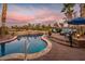 Inviting backyard view of a pool, fire pit, and outdoor lounge area with golf course views and landscaped greenery at 22329 N Padaro Dr, Sun City West, AZ 85375