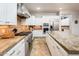 Modern kitchen with stainless steel appliances, granite countertops, white cabinets, a range hood, and tile flooring at 22329 N Padaro Dr, Sun City West, AZ 85375