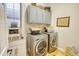 Well-lit laundry room with modern washer and dryer, sink, grey cabinets, and stylish decor at 22462 N 80Th Ln, Peoria, AZ 85383