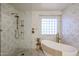 Bathroom featuring a soaking tub, walk-in shower, marble accents and a garden window at 22927 N 41St St, Phoenix, AZ 85050