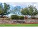 Stone entrance to Trilogy with well-maintained landscaping, flowers, and trees creating a welcoming atmosphere at 29412 N 128Th Ln, Peoria, AZ 85383