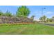 Community stone entrance with vibrant flowerbeds and a manicured lawn, creating a welcoming atmosphere at 29412 N 128Th Ln, Peoria, AZ 85383