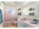 Charming pink bathroom featuring a bathtub with glass doors and a vanity with a sink at 3511 N Miller Rd, Scottsdale, AZ 85251