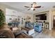 Relaxing living room with cozy seating, a ceiling fan, hardwood floors, and a large flat screen television at 3716 E Andre Ave, Gilbert, AZ 85298