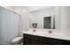 Bathroom featuring double sinks, dark cabinets, and a shower with a patterned curtain at 40433 W Hensley Way, Maricopa, AZ 85138