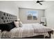 Bright bedroom features a large upholstered headboard and a window with blinds at 40433 W Hensley Way, Maricopa, AZ 85138