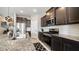 Modern kitchen with stainless steel appliances, granite countertops, and dark wood cabinetry at 40433 W Hensley Way, Maricopa, AZ 85138