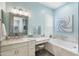 Bathroom featuring double sinks, white cabinets, a bathtub with gray stone-look trim, and blue walls at 435 E Coconino Pl, Chandler, AZ 85249