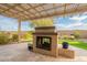 Outdoor fireplace, travertine tile, synthetic grass, and neutral stucco in backyard at 4709 E Blue Spruce Ln, Gilbert, AZ 85298