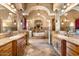 Elegant bathroom featuring dual sinks, stone floors, and a soaking tub at 5203 N 179Th Dr, Litchfield Park, AZ 85340