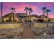 Twilight view of a stone accented home with a brick entry walk, desert landscaping, and mature palm trees at 5203 N 179Th Dr, Litchfield Park, AZ 85340