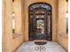 Daytime view of the ornate iron front door, tiled entry, stucco exterior and manicured landscaping at 5203 N 179Th Dr, Litchfield Park, AZ 85340