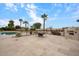 The backyard features an outdoor fireplace, barbecue area, and a pristine pool surrounded by palm trees at 5203 N 179Th Dr, Litchfield Park, AZ 85340