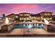Twilight view of a backyard with a stunning pool with water features, and an outdoor seating area at 5203 N 179Th Dr, Litchfield Park, AZ 85340