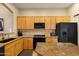 Well-lit kitchen featuring a center island with granite countertops, light wood cabinets, and black appliances at 7445 E Eagle Crest Dr # 1094, Mesa, AZ 85207