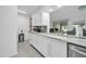 White kitchen with stainless steel dishwasher, white cabinetry, tile floors and marble countertops at 10646 W Tropicana Cir, Sun City, AZ 85351