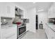 Bright white kitchen featuring stainless steel appliances and range hood, granite countertops, and white cabinetry at 10646 W Tropicana Cir, Sun City, AZ 85351