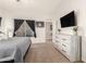 Bright main bedroom with a large window, TV, dresser, and ensuite bathroom access at 11330 W Eden Mckenzie Dr, Surprise, AZ 85378